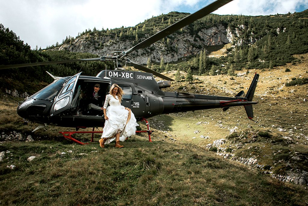 Braut steigt aus einem Helikopter in den Bergen für ihre Hochzeit