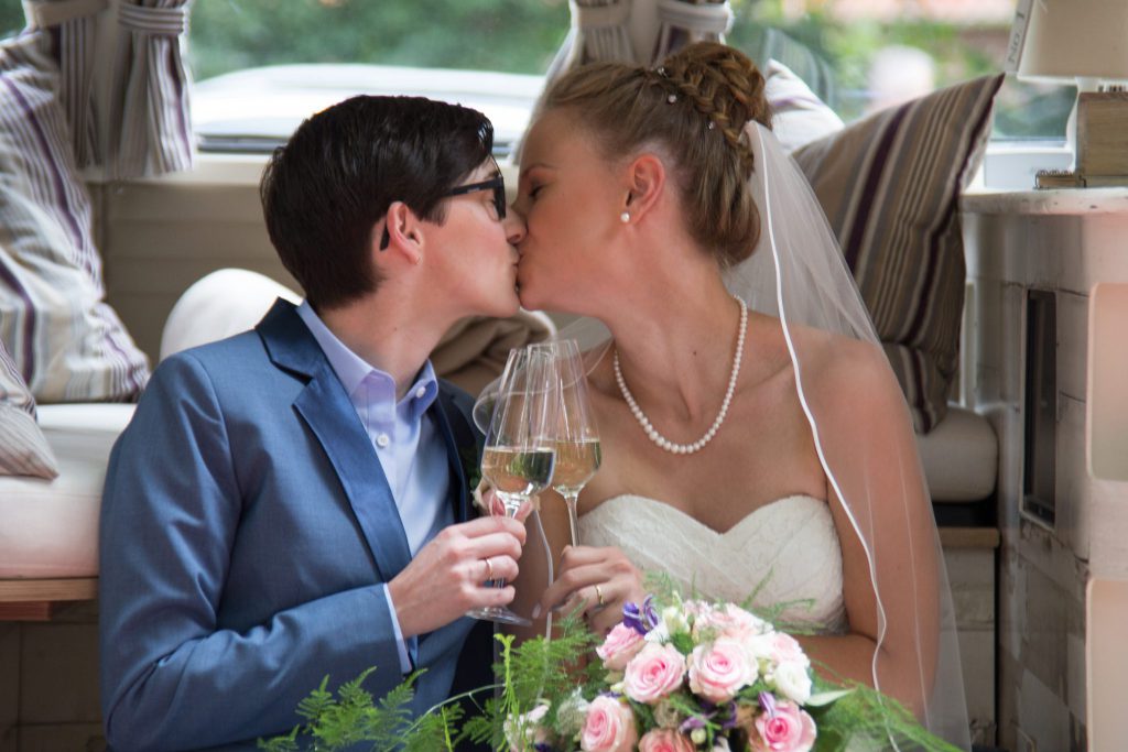 Braut und Braut küssen sich nach der queeren Hochzeit | Strauß & Fliege