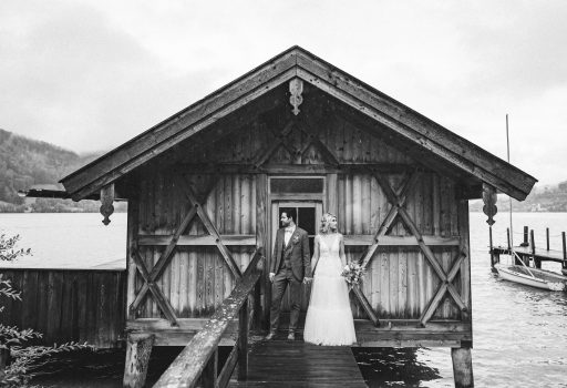Brautpaar vor Holzhütte auf dem Steg am See