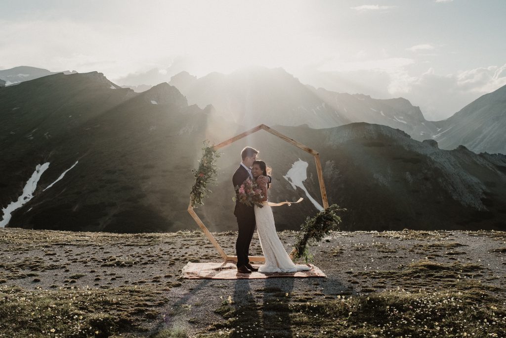 Brautpaar auf Bergspitze bei Sonnenuntergang