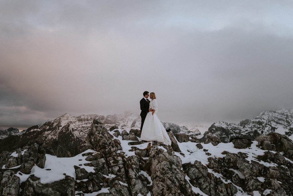 Elopement Hochzeit: Brautpaar auf Bergspitze im Nebel
