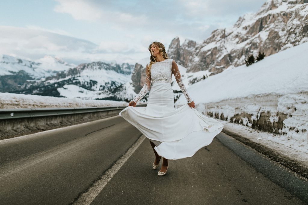Braut mit Kleid im Boho-Stil mitten in den verschneiten Alpen