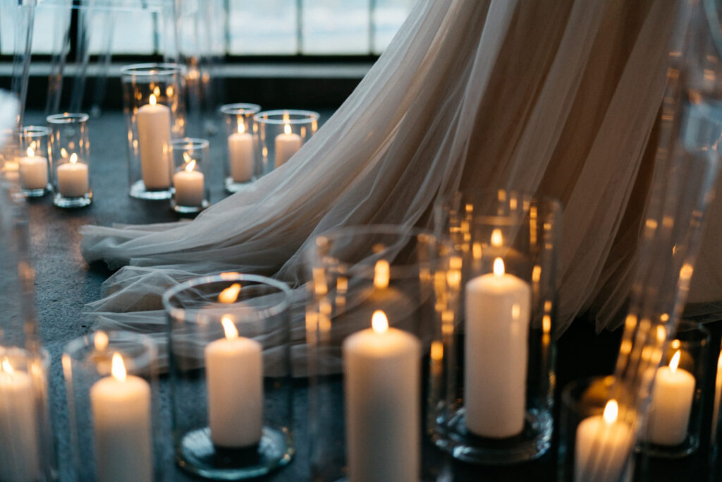 Die Schleppe einer Braut beim Einzug zwischen Kerzen