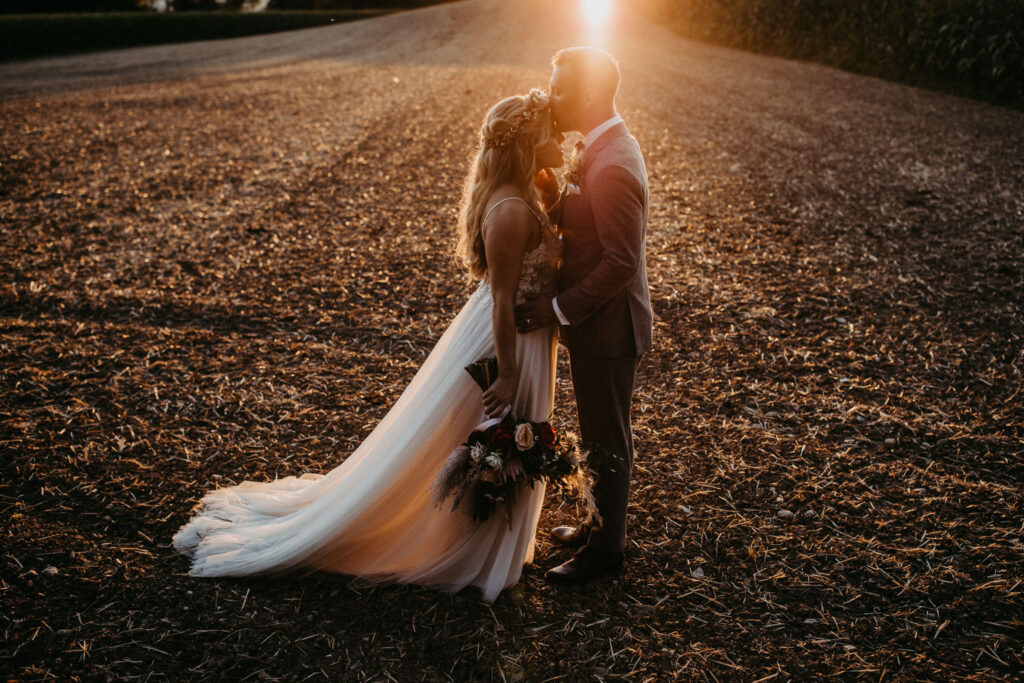 Brautpaar auf Wiese im Sonnenuntergang | Strauß & Fliege
